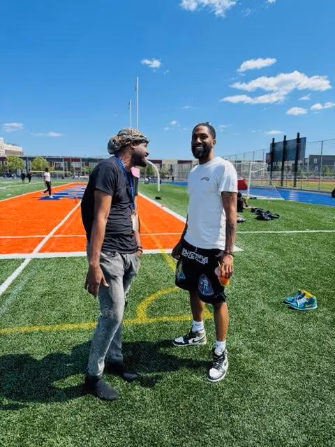 Two men laughing together on a school athletic field