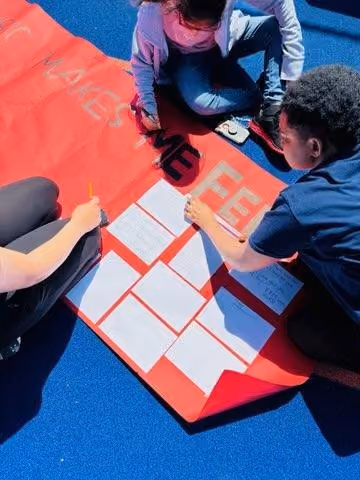 Students collaborating on a large red poster outdoors