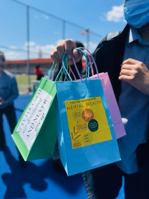 Student holding colorful gift bags with mental health awareness messages