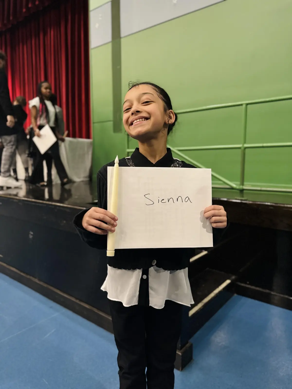 Student named Sienna smiling and holding a sign at school event