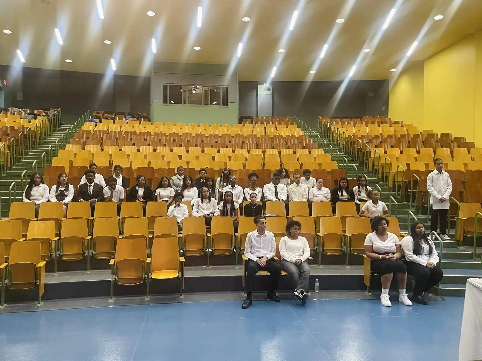 Students in formal attire seated in school auditorium for an event