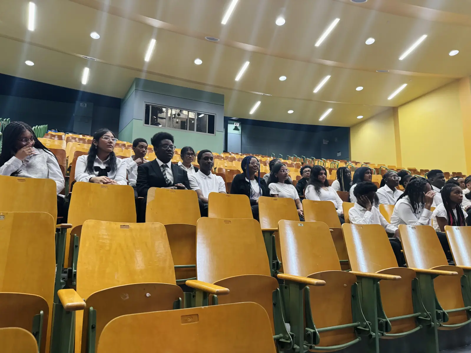 Students in formal attire seated in a school auditorium