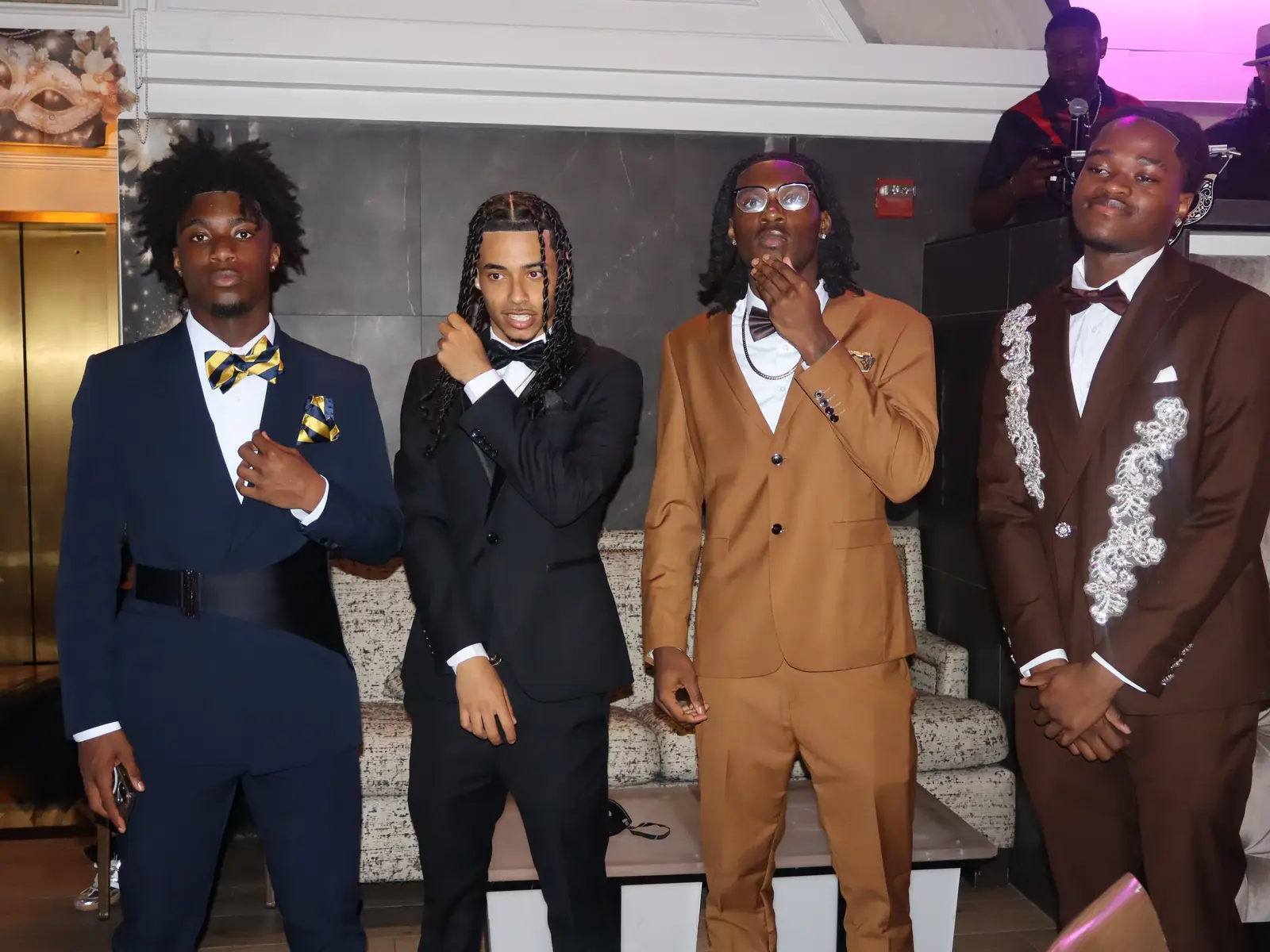 Four male students in formal suits posing at prom