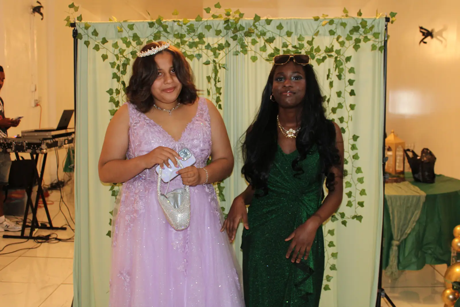 Two students posing in formal gowns at a school prom event