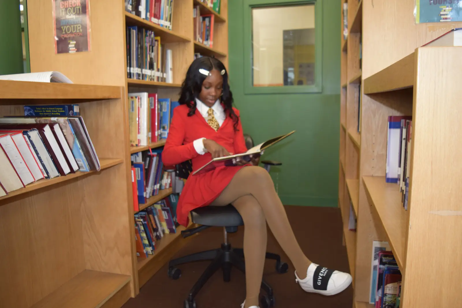 Student in school uniform reading a book in the library
