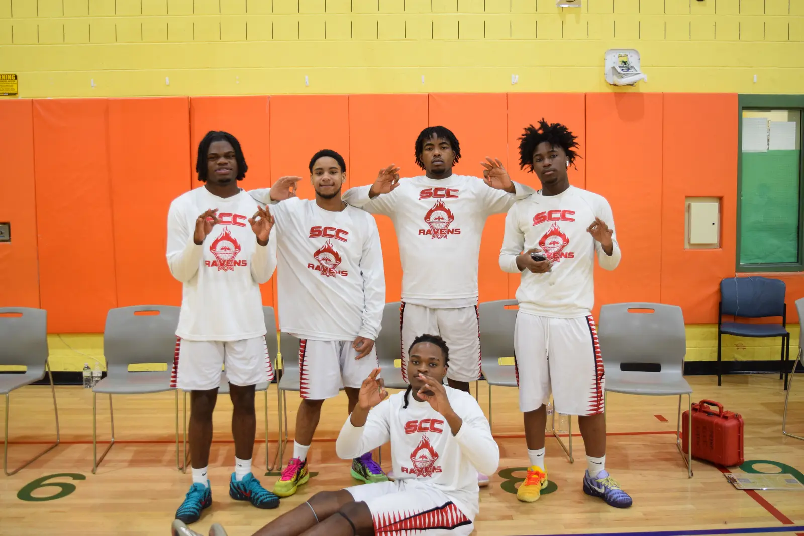 SCC Ravens basketball players posing together in school gymnasium