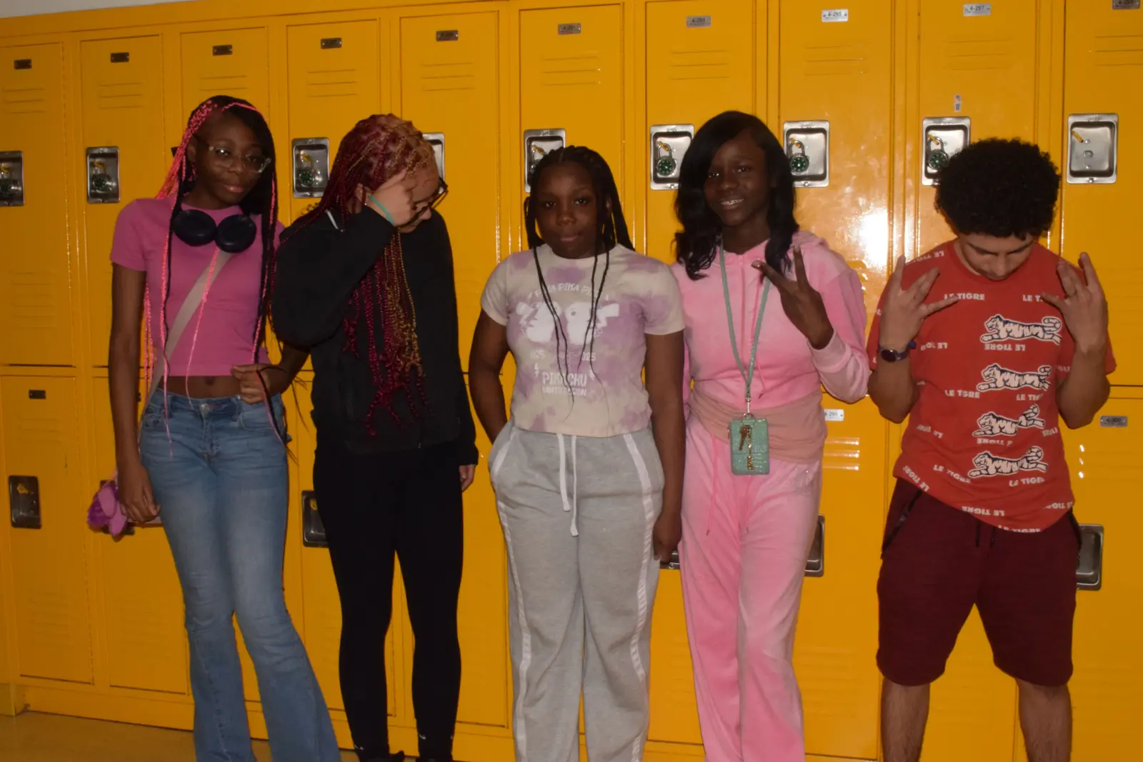 Five students posing together in front of yellow school lockers