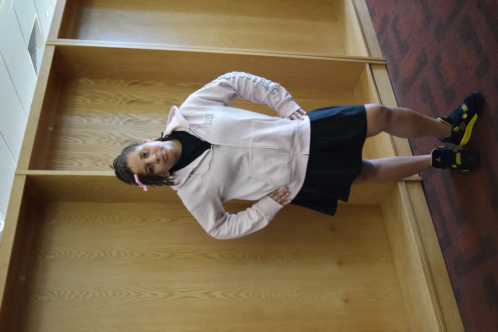 Student posing on wooden steps in school hallway