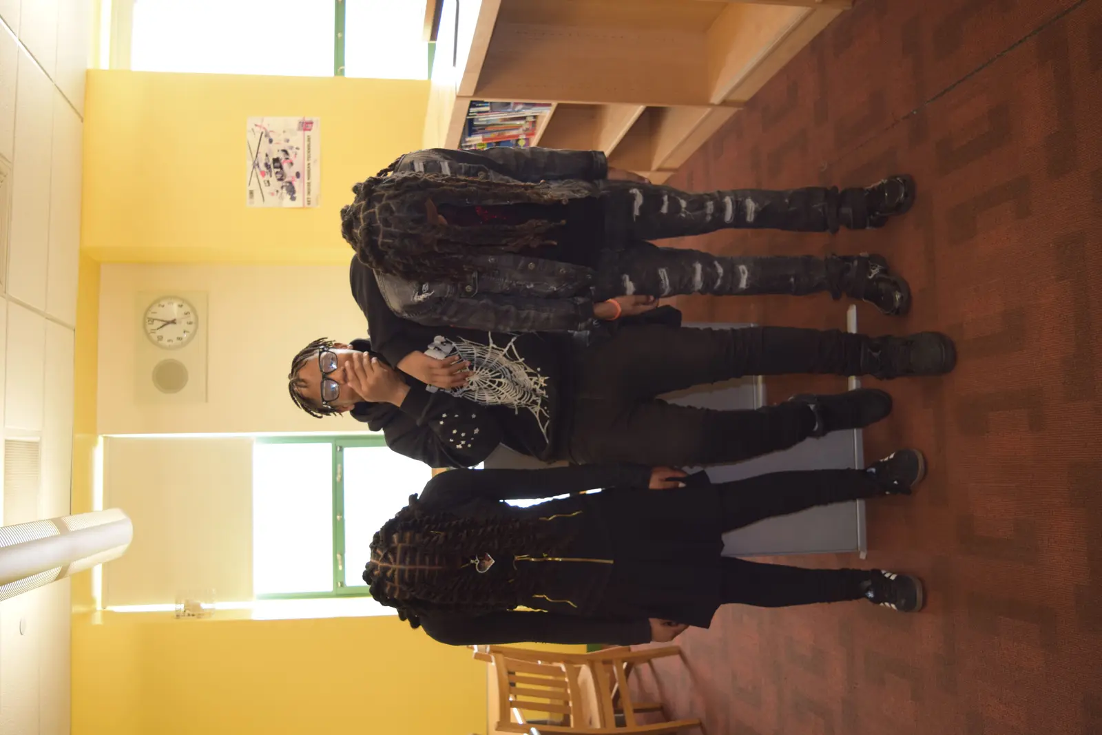 Three students standing together in a school hallway