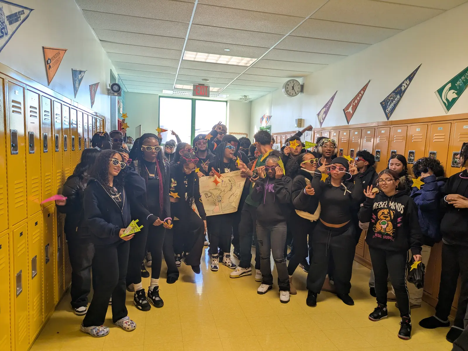Students celebrating in school hallway wearing fun glasses and holding star props
