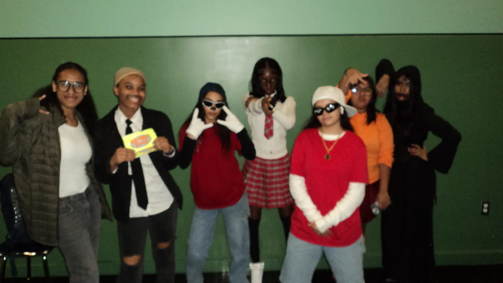 Seven students in themed costumes posing together at a school event