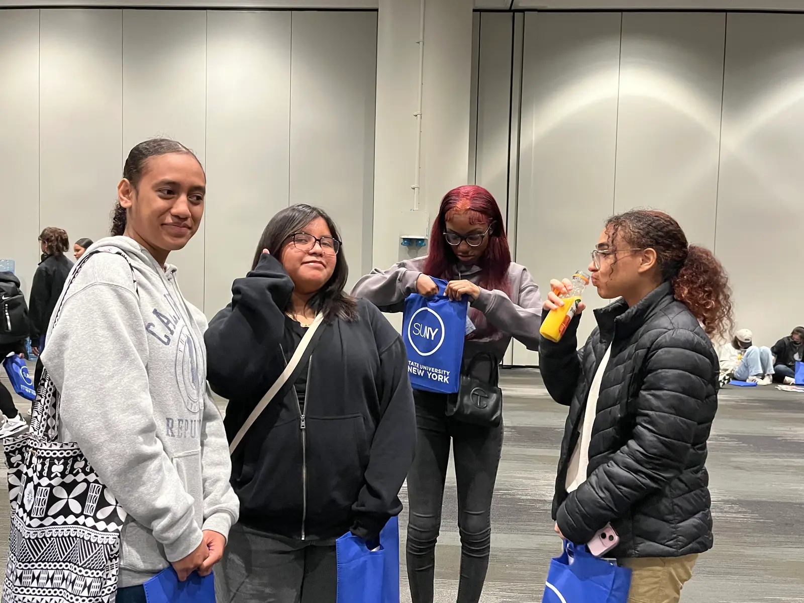 Students holding SUNY tote bags at a college fair event