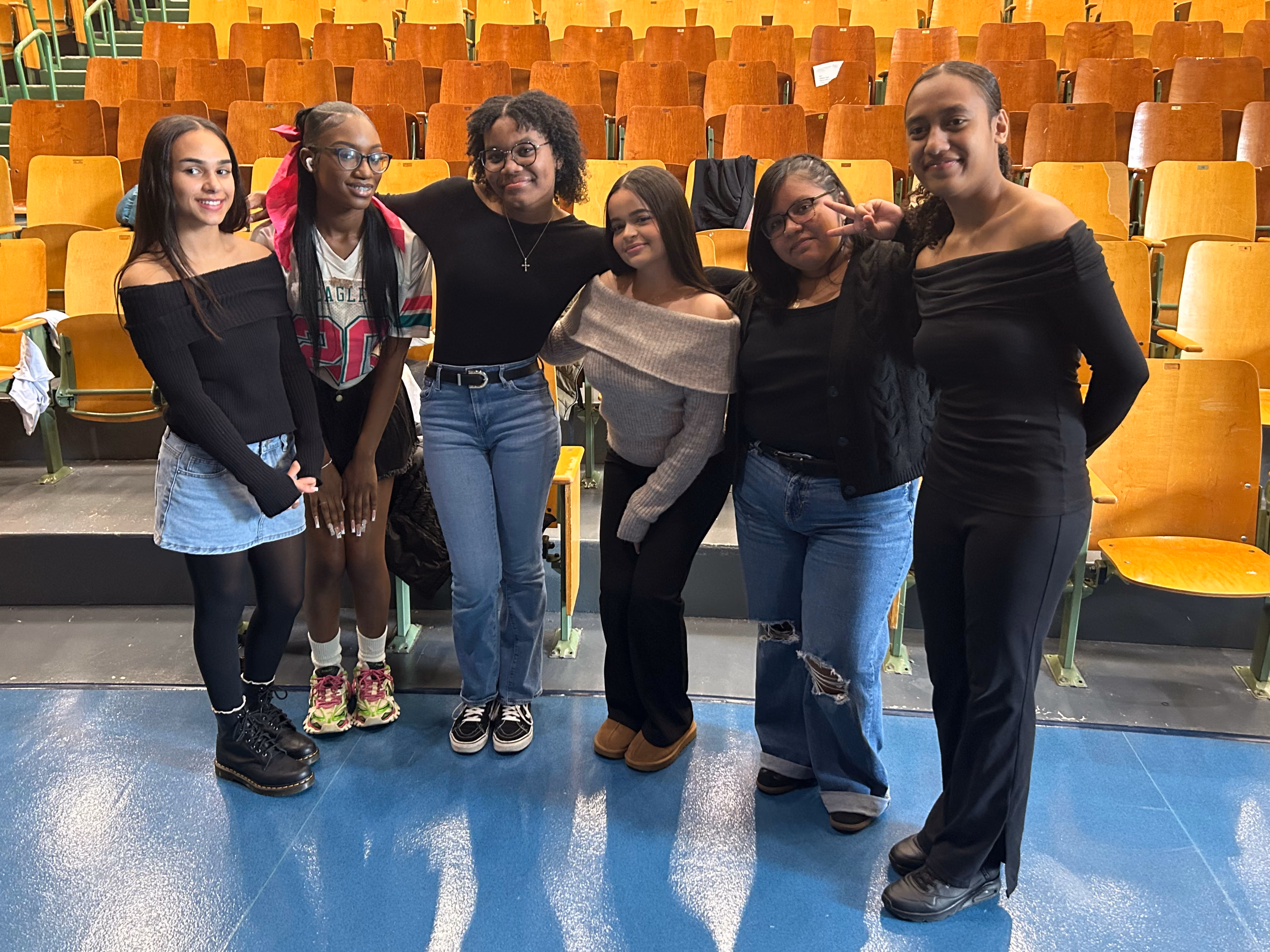 Six female students posing together in school auditorium seating area