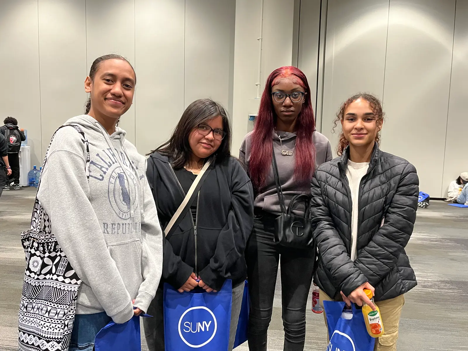 Four students posing together at a SUNY college fair event