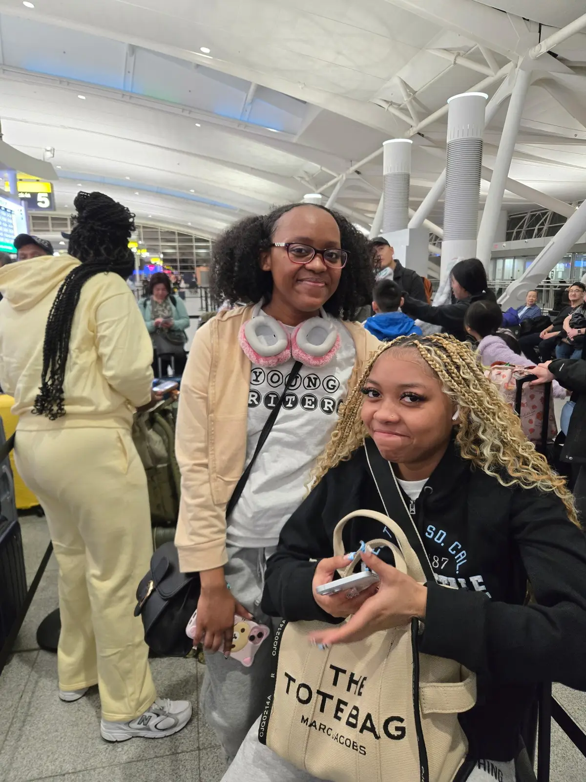 Two students wearing Young Writers shirts pose at airport terminal