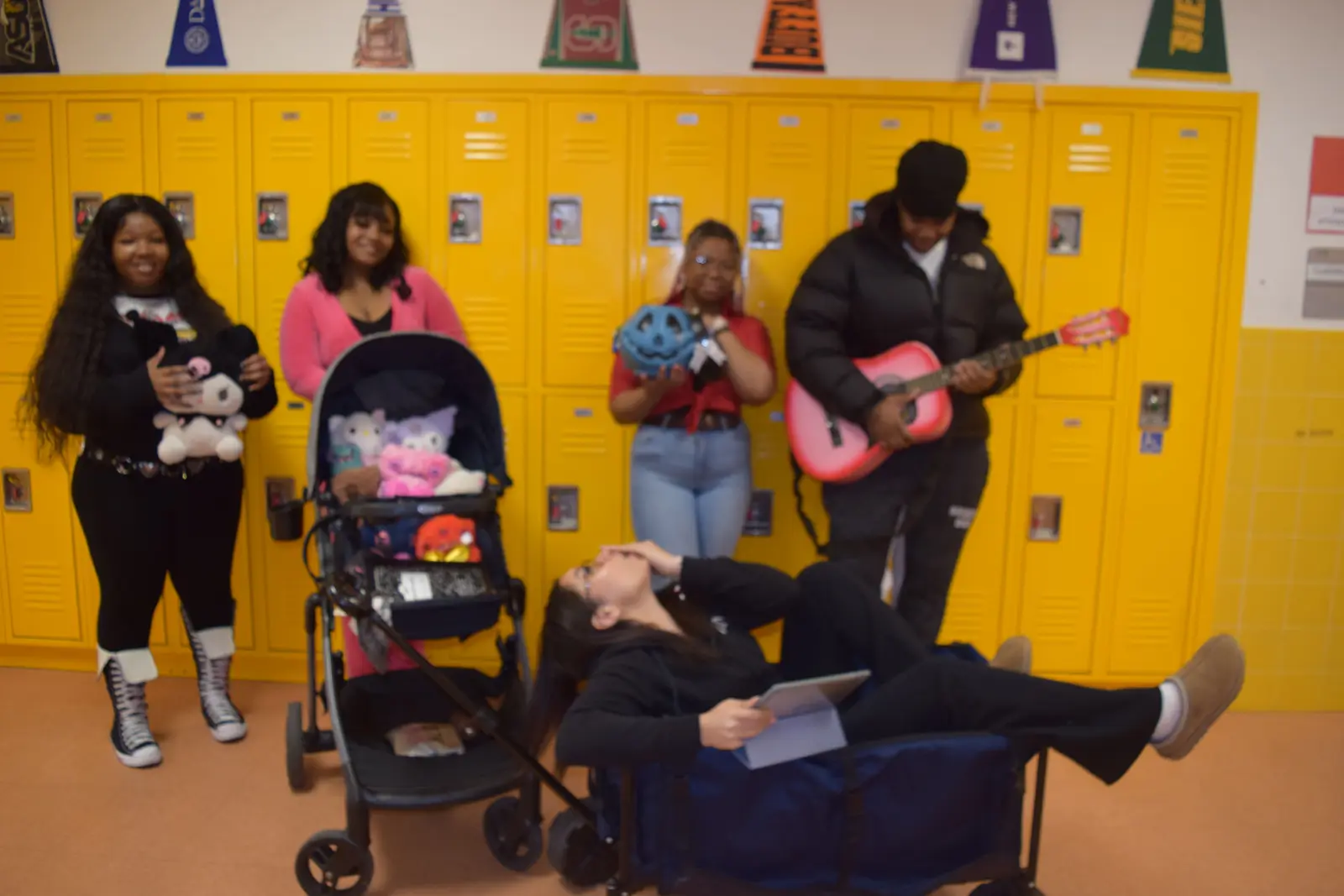 Students posing playfully in school hallway near yellow lockers