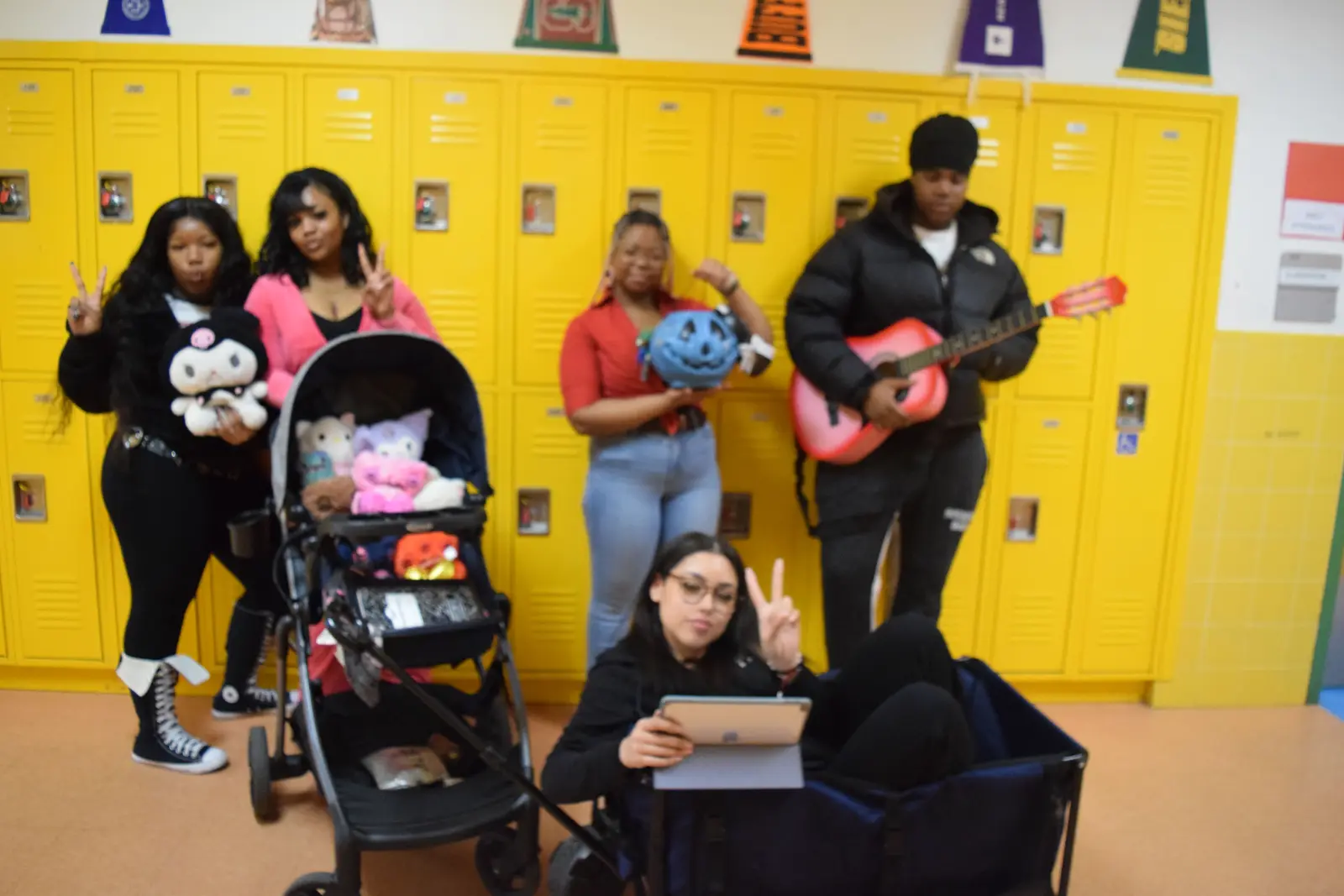 Students posing with guitar stroller and tablet by school lockers