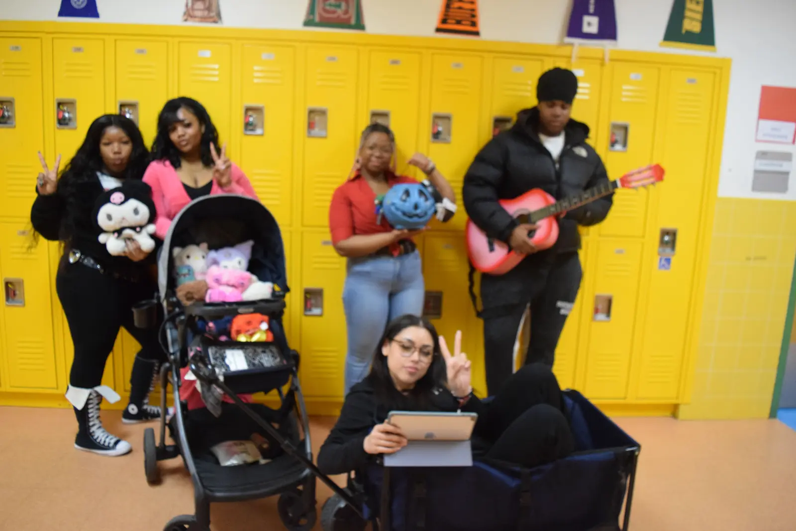 Students pose in school hallway with guitar toys and Halloween props