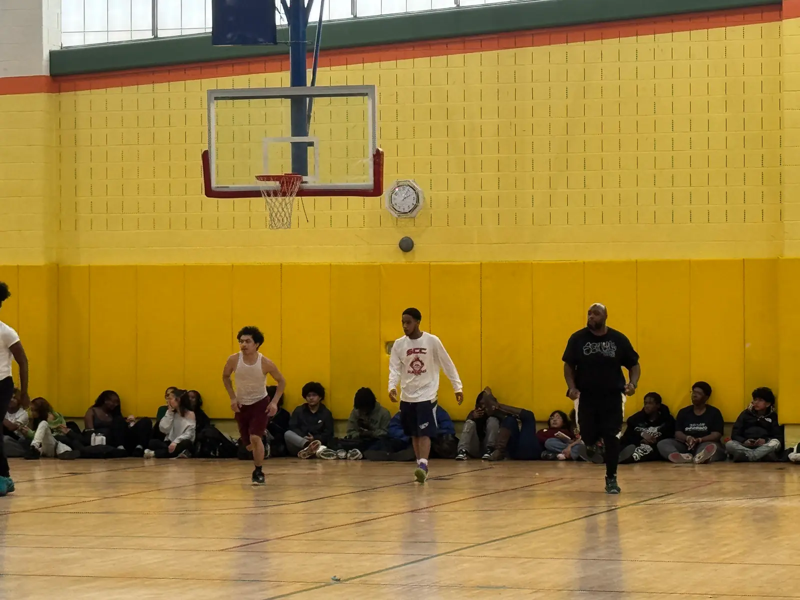 Students playing basketball in school gymnasium with spectators watching