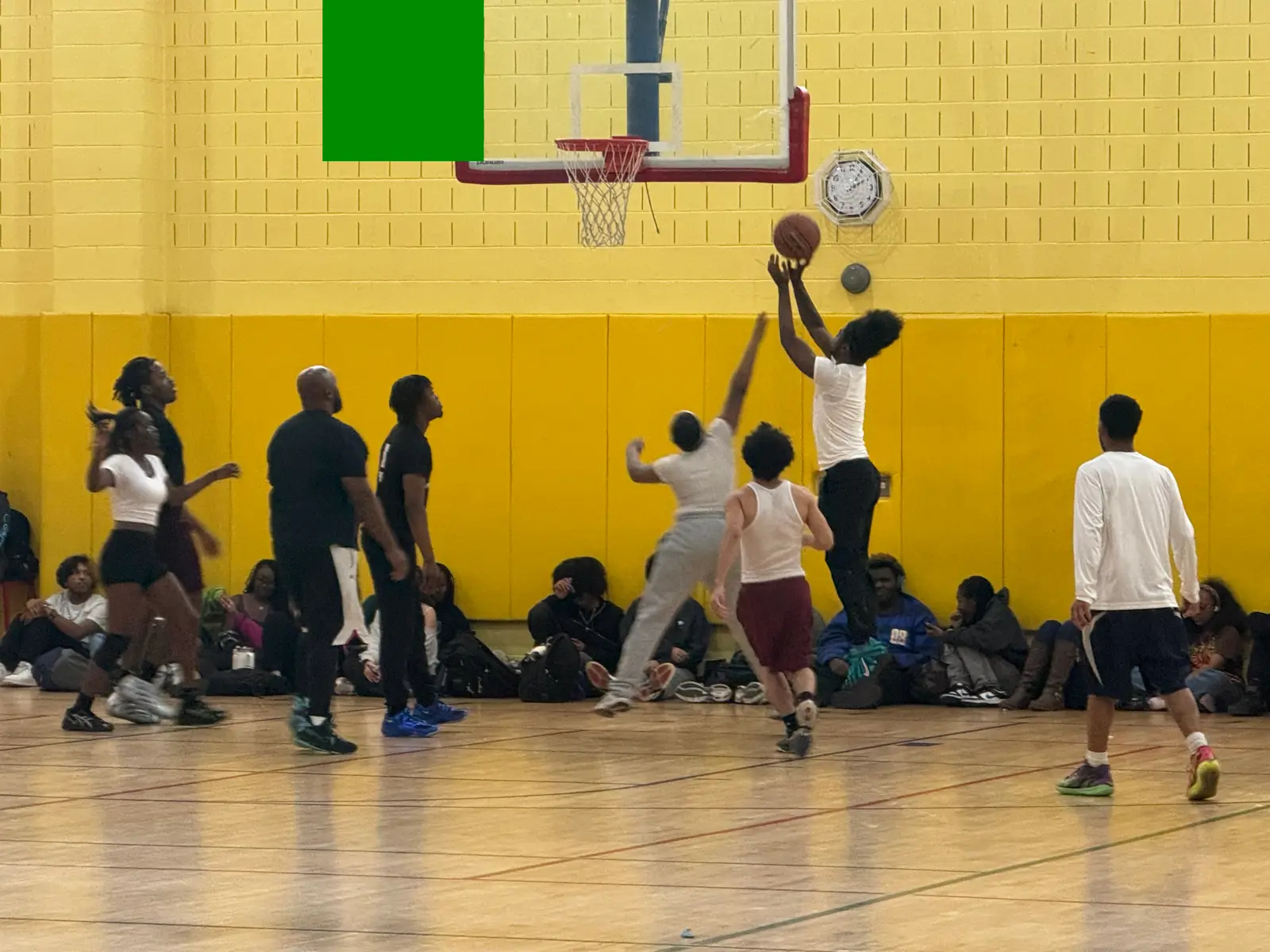 Students playing basketball in a school gymnasium with spectators watching