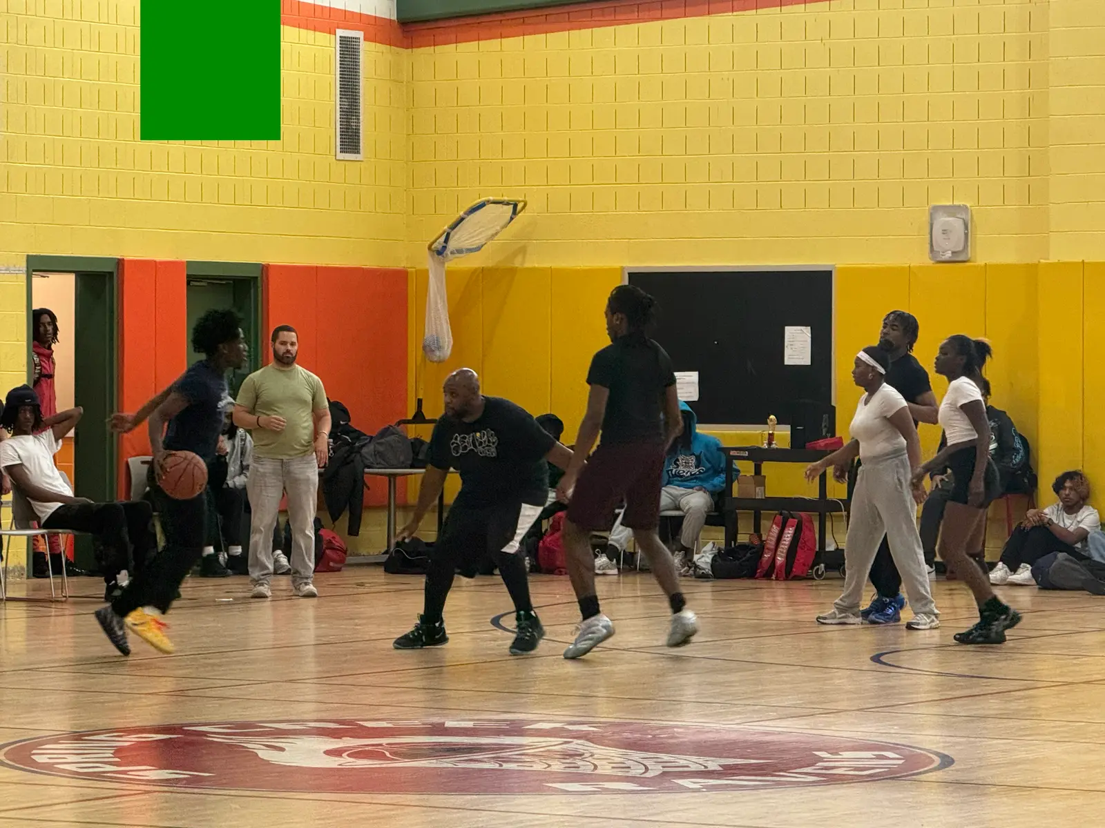 Students and adults playing basketball in a school gymnasium