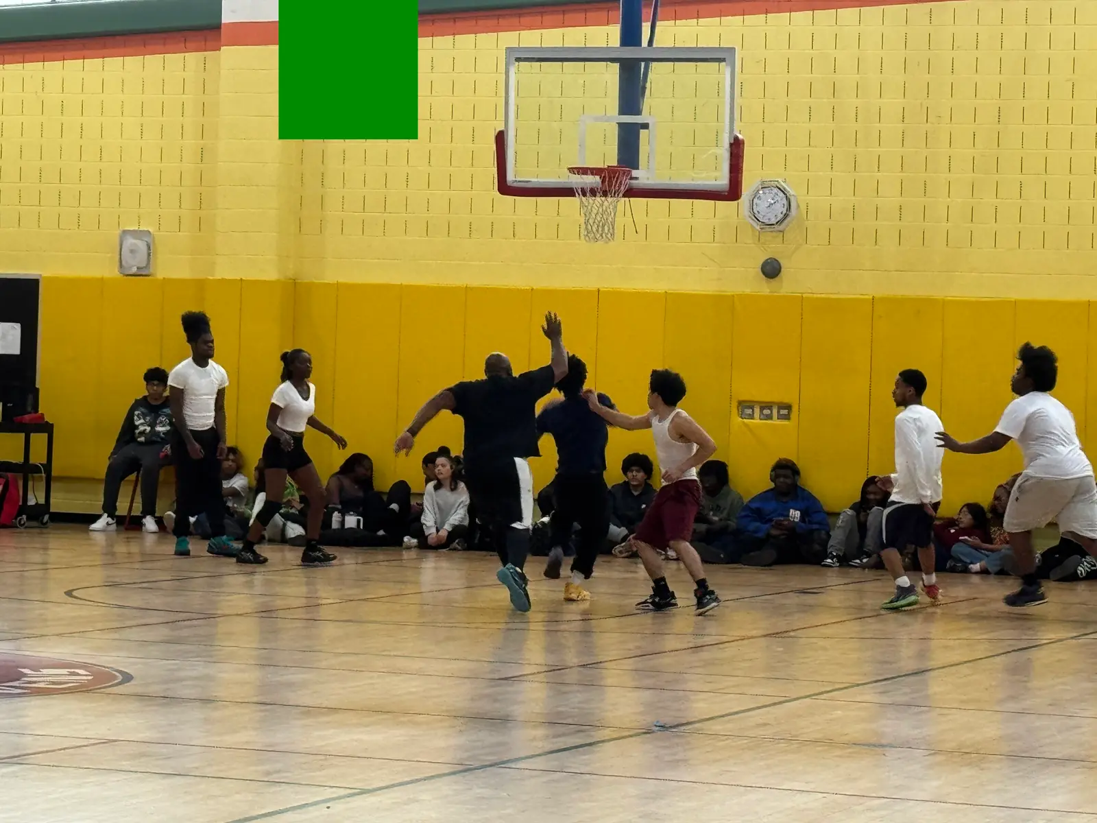 Students playing basketball in school gymnasium with spectators watching