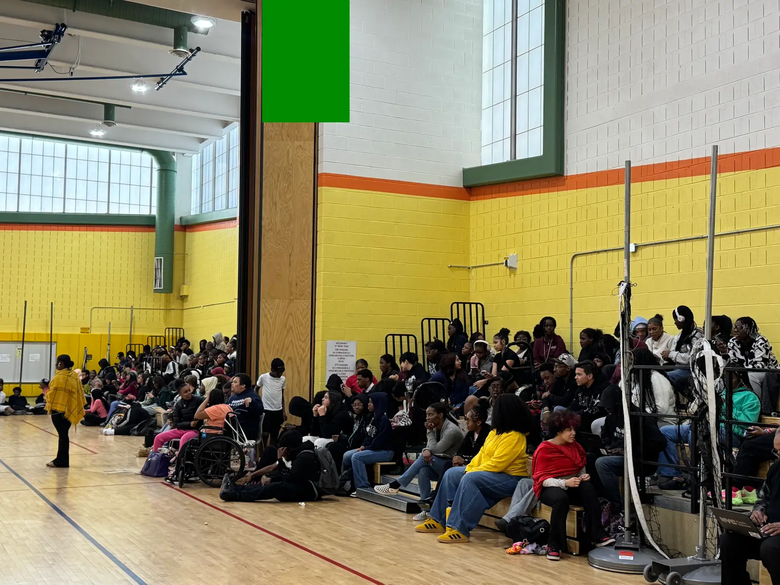 Students gathered in school gymnasium bleachers during an assembly event