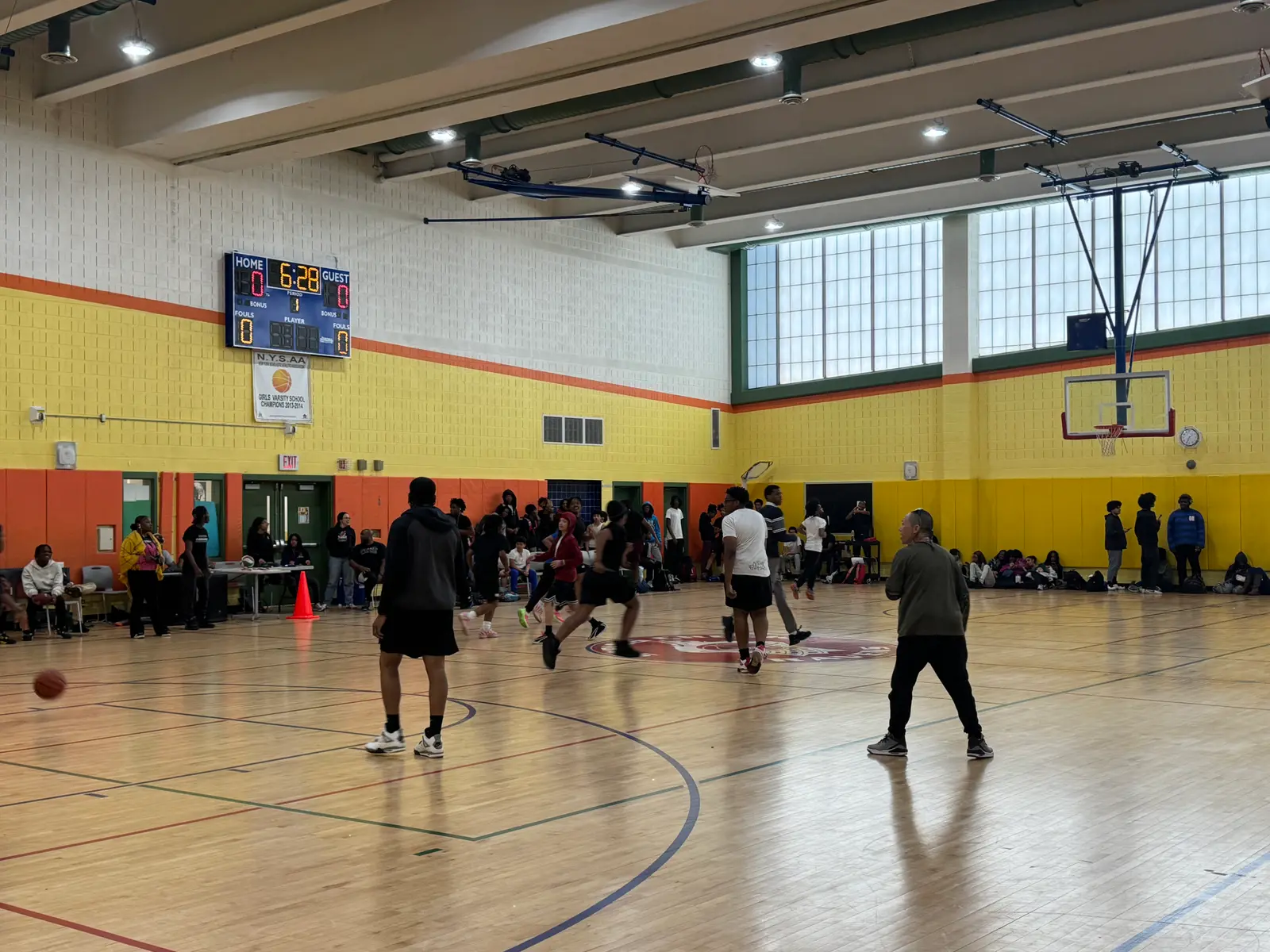 Students playing basketball in school gymnasium during a game