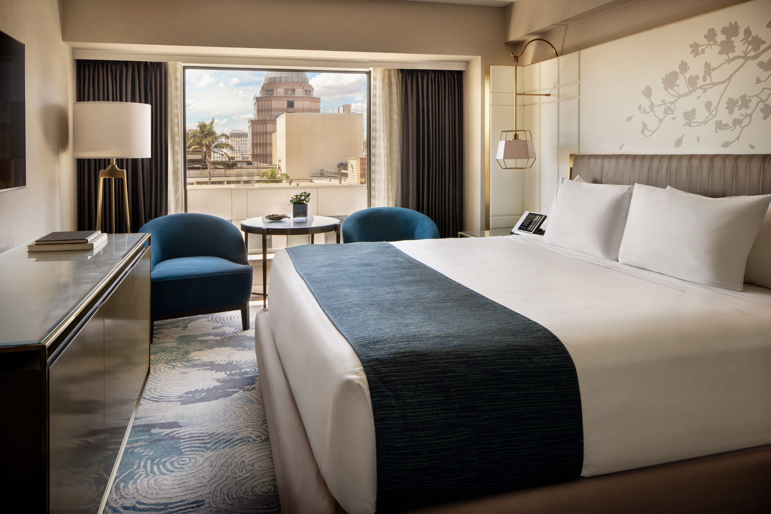 Deluxe king room with blue chairs and large window.