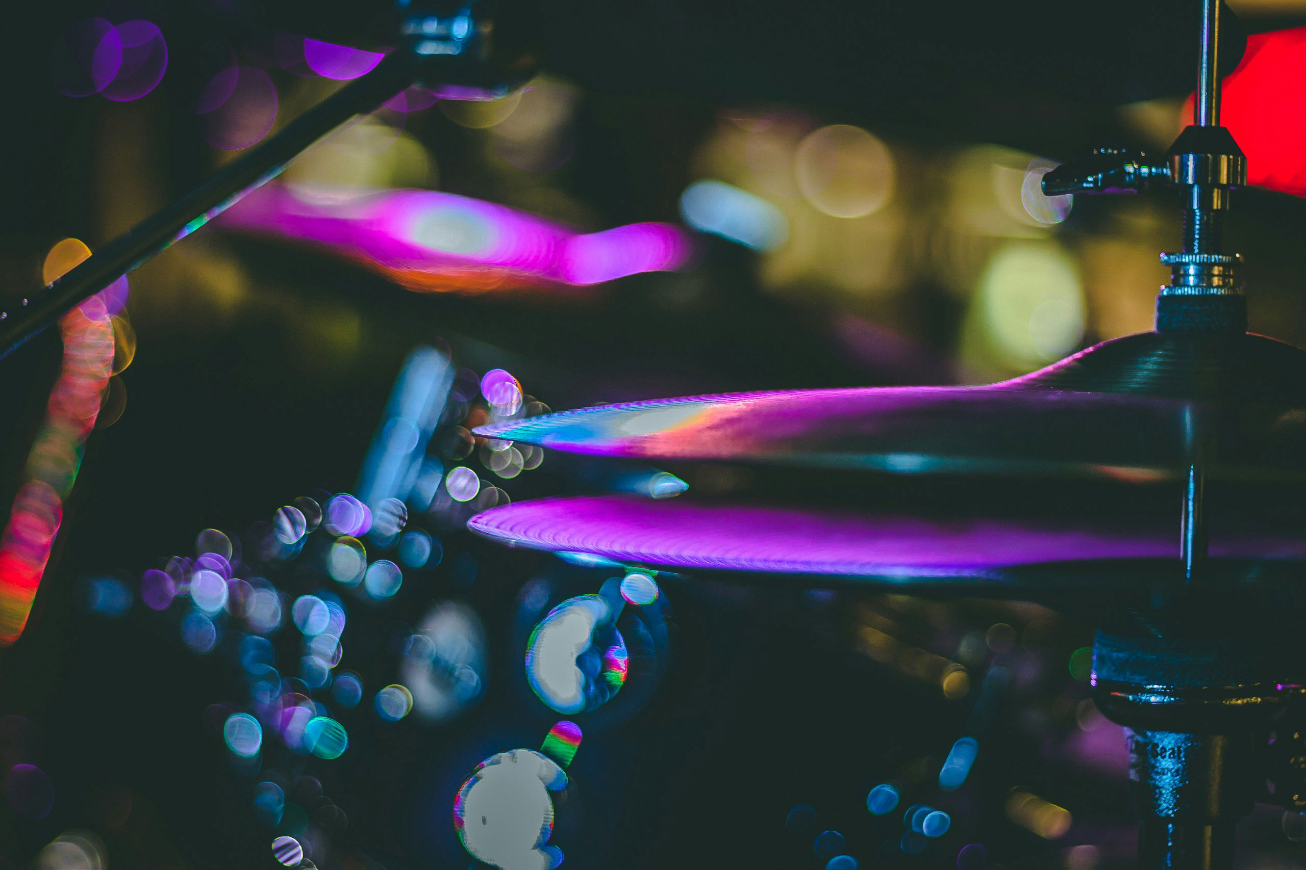 Close-up of drum cymbals under colorful stage lights