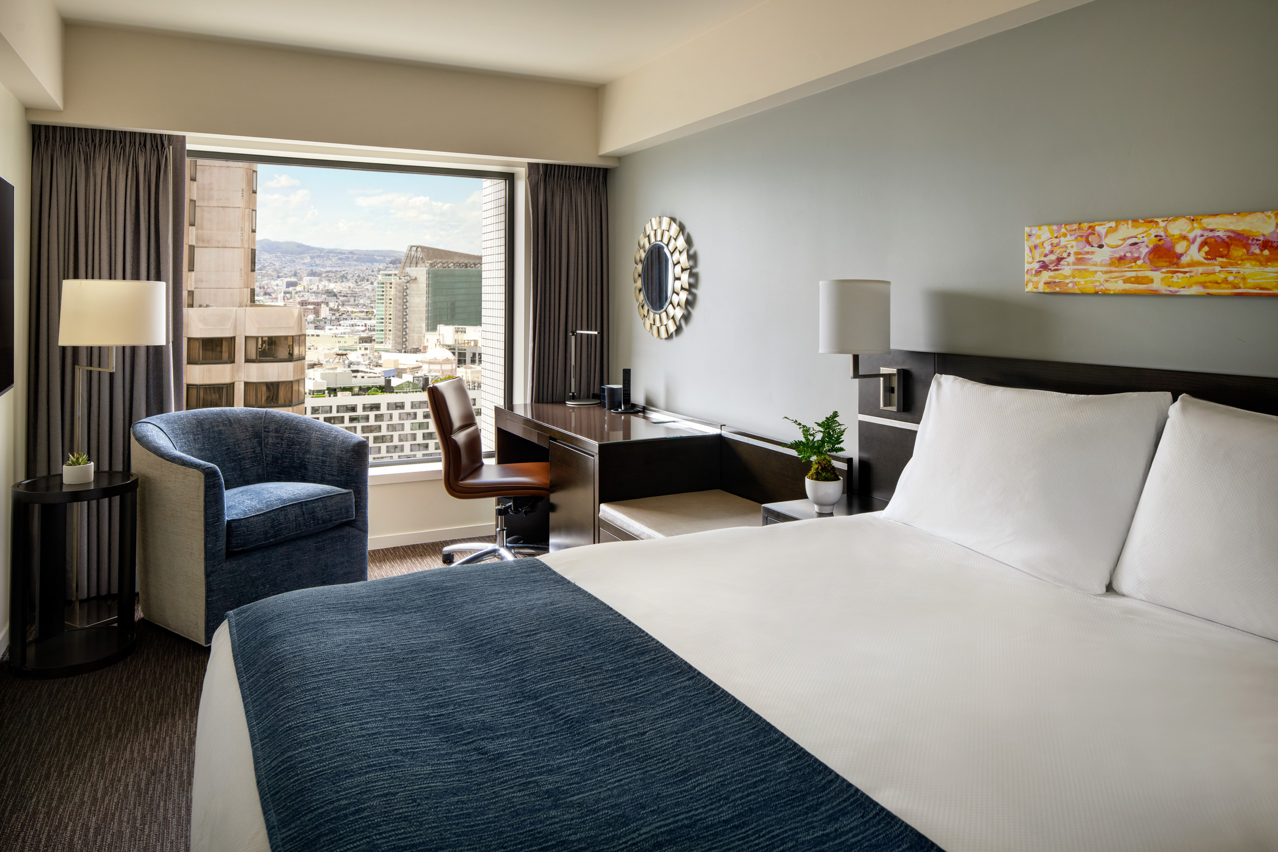 Petite queen room with chair, desk, and city view.