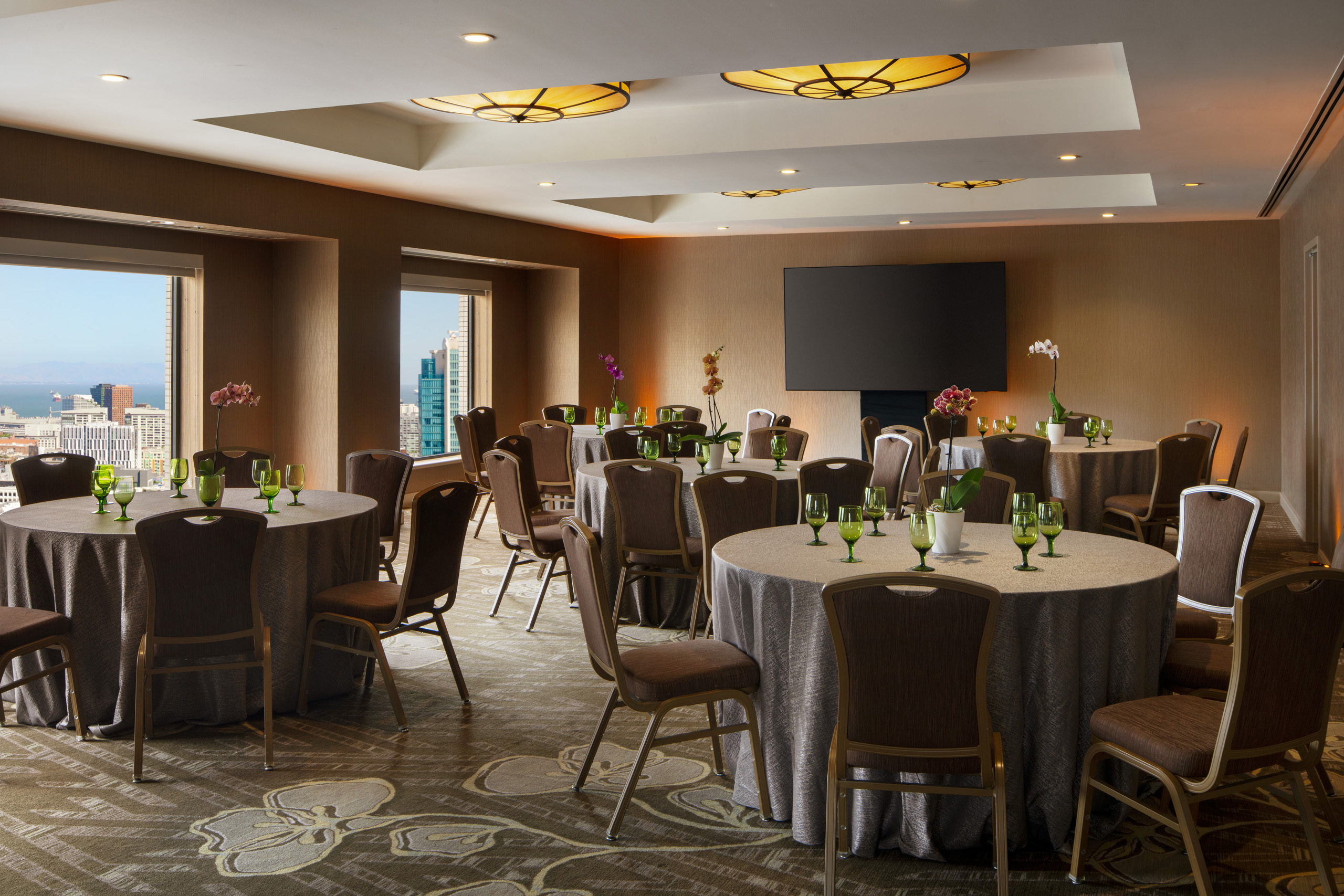 Meeting room with round banquet tables and city views.
