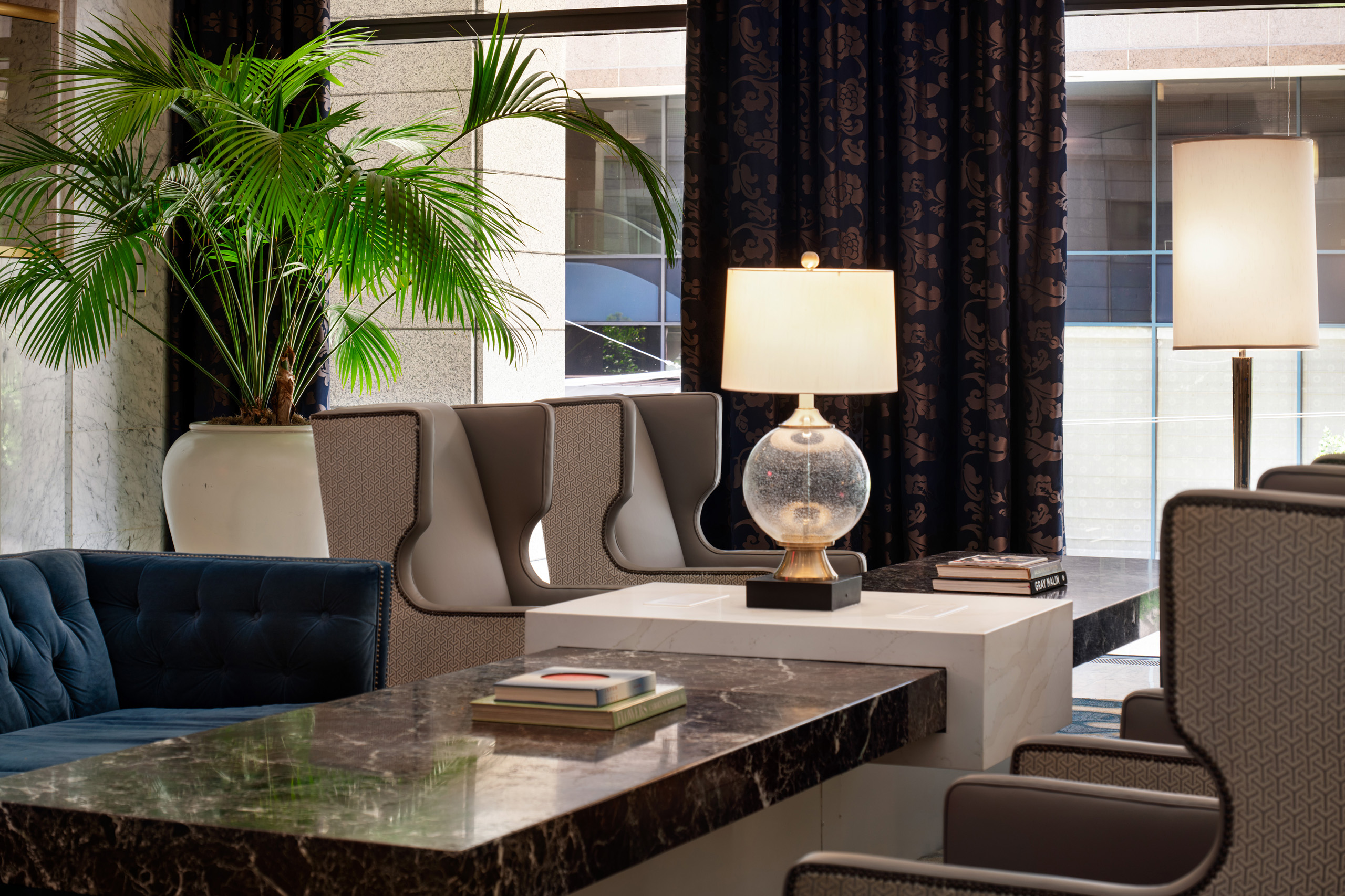 Marble table with elegant seating and potted palm in hotel lobby.