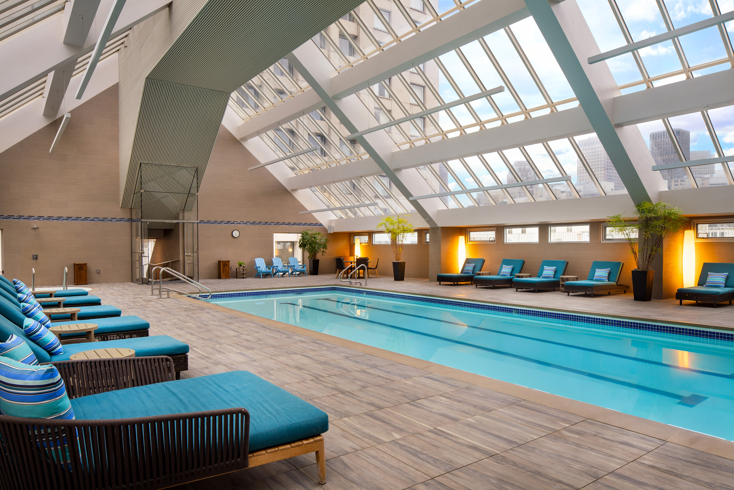 Indoor rooftop pool with lounge chairs and skylight ceiling
