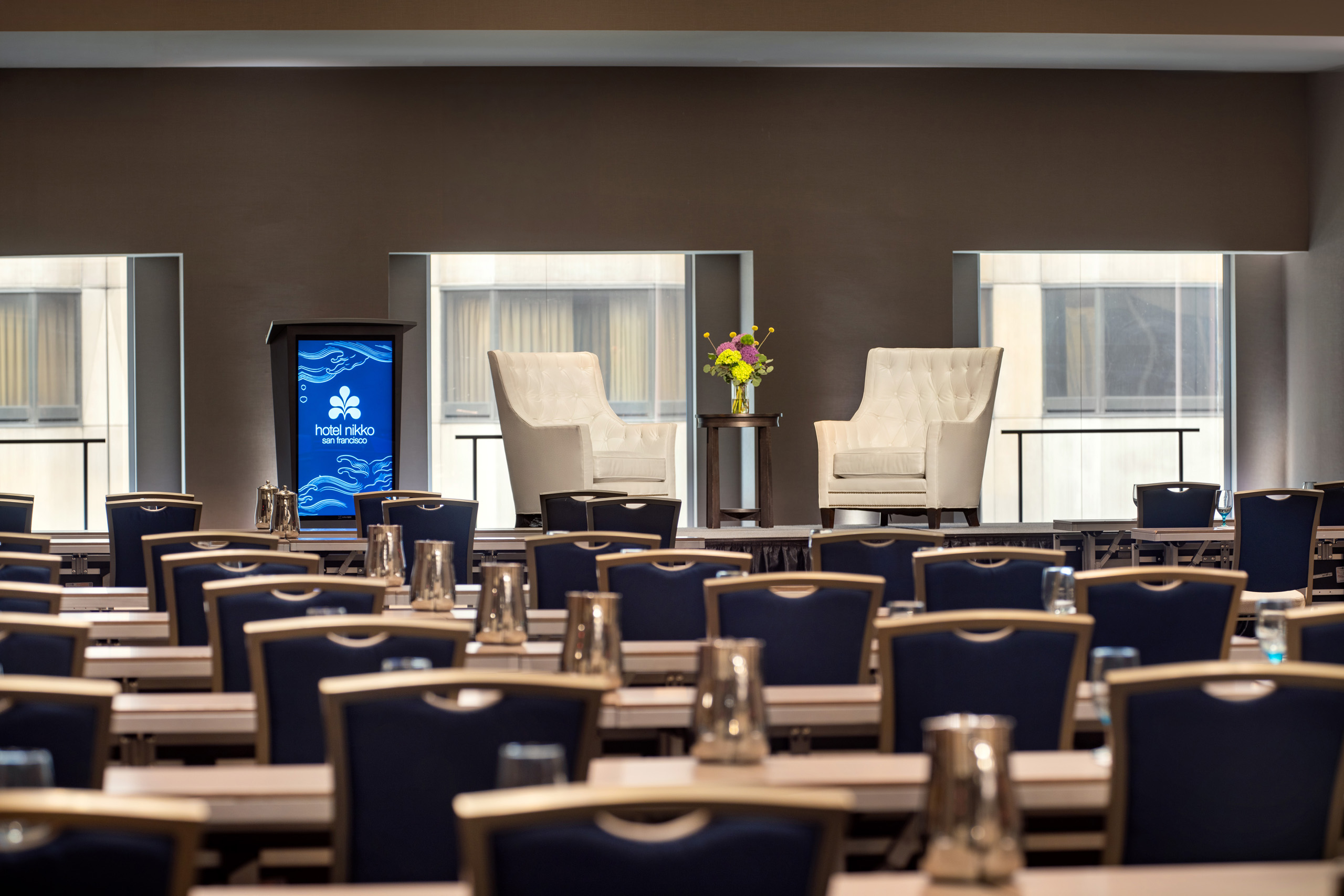 Spacious ballroom classroom setup with stage and presentation screens.