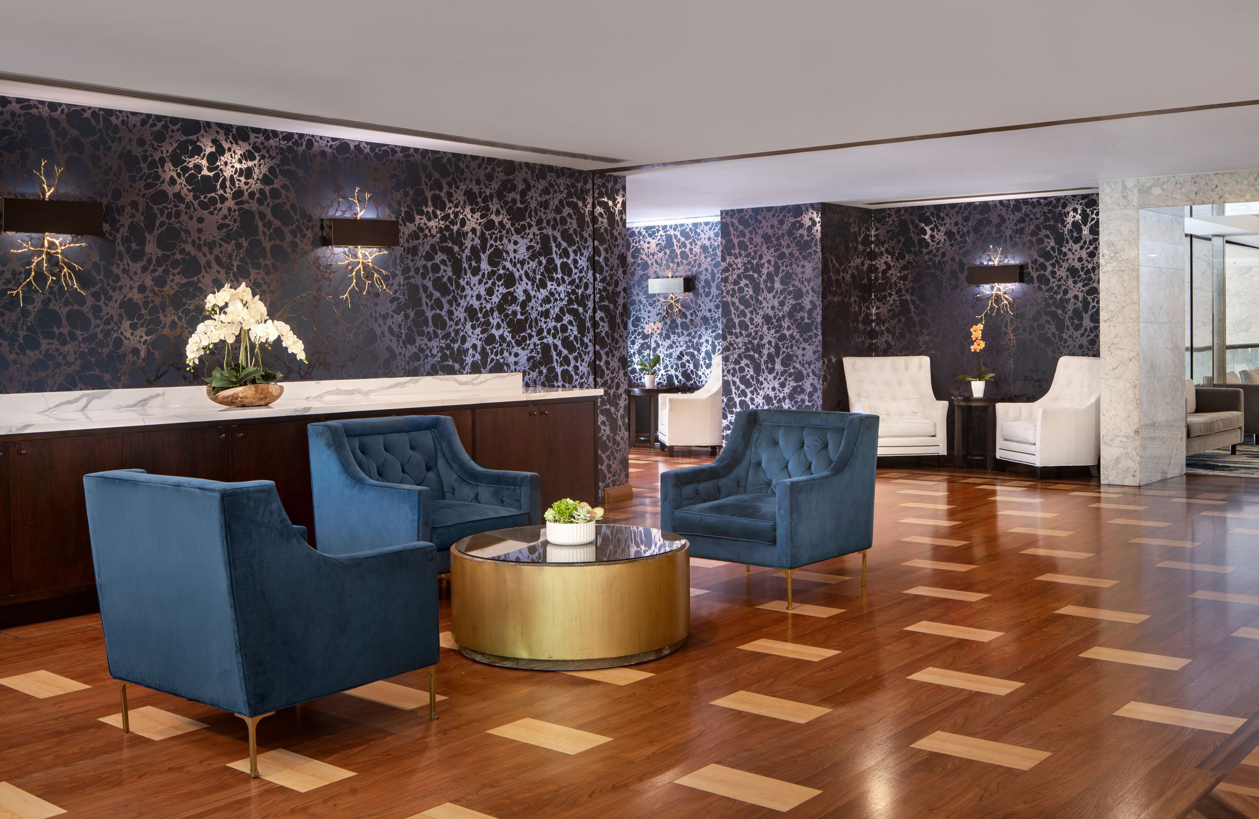 Hotel reception area with blue chairs and patterned walls.