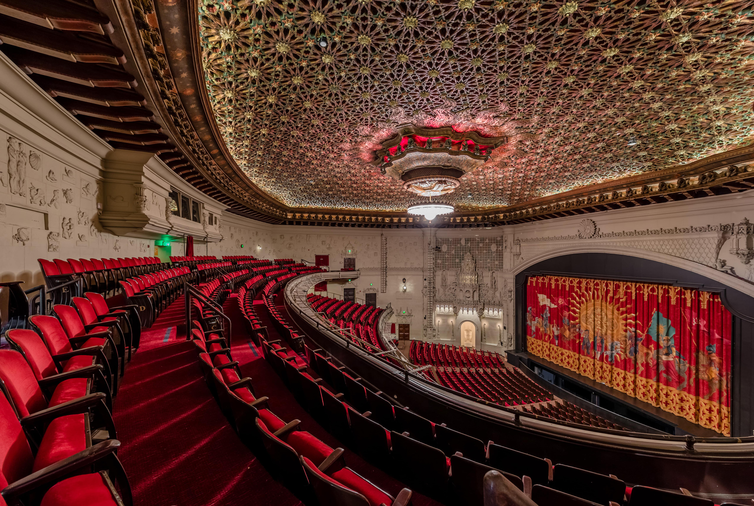 Ornate theater interior with red seats and decorative ceiling.
