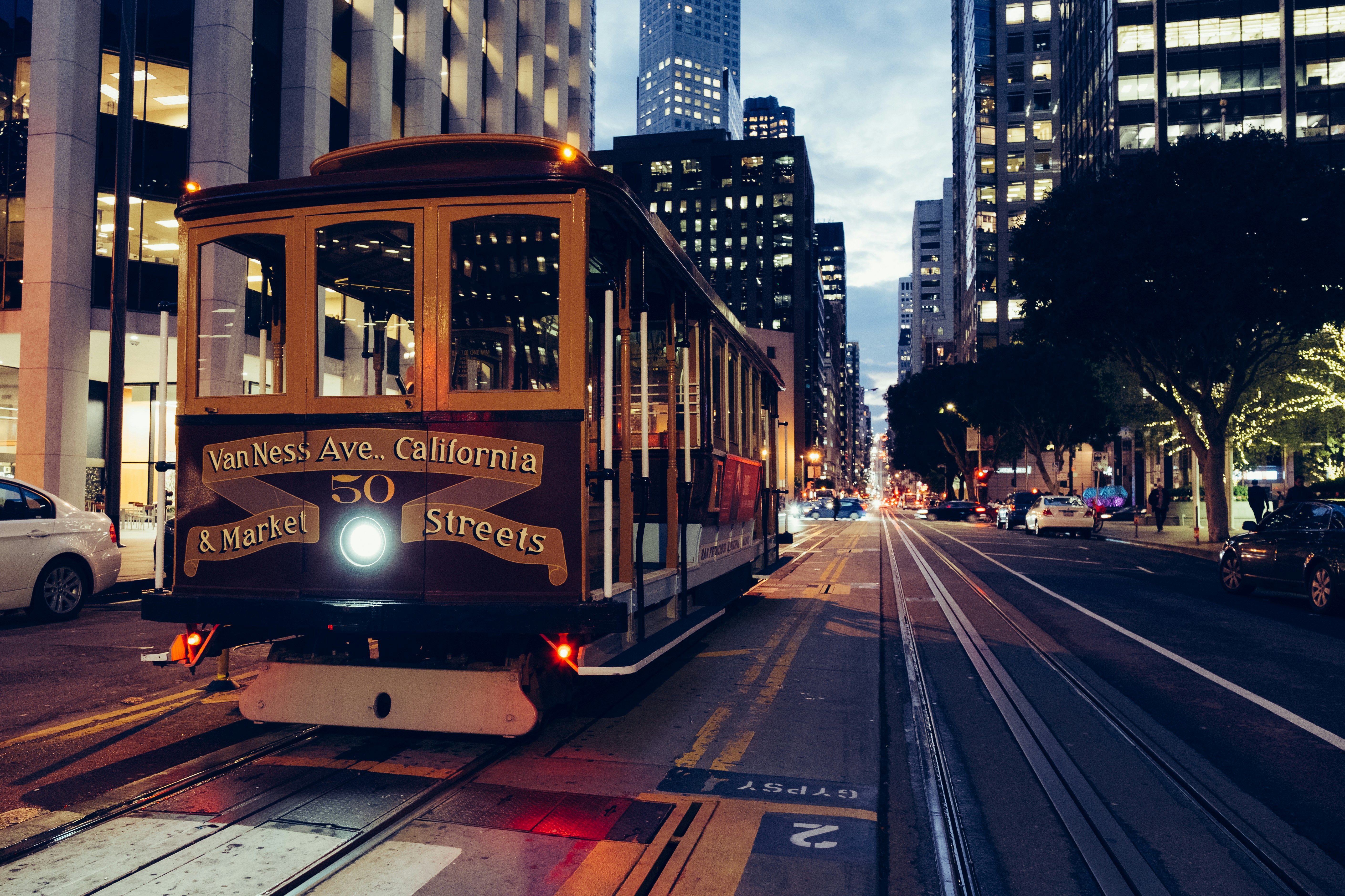 San Francisco cable car traveling through downtown at dusk.
