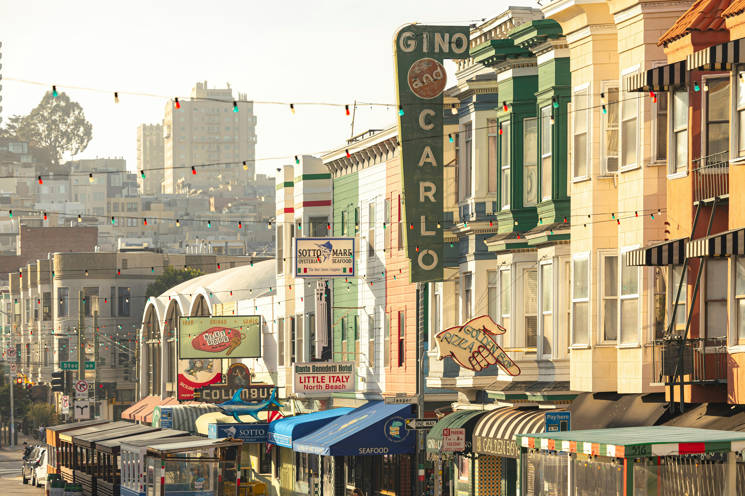 Colorful North Beach buildings and restaurant signs along street.