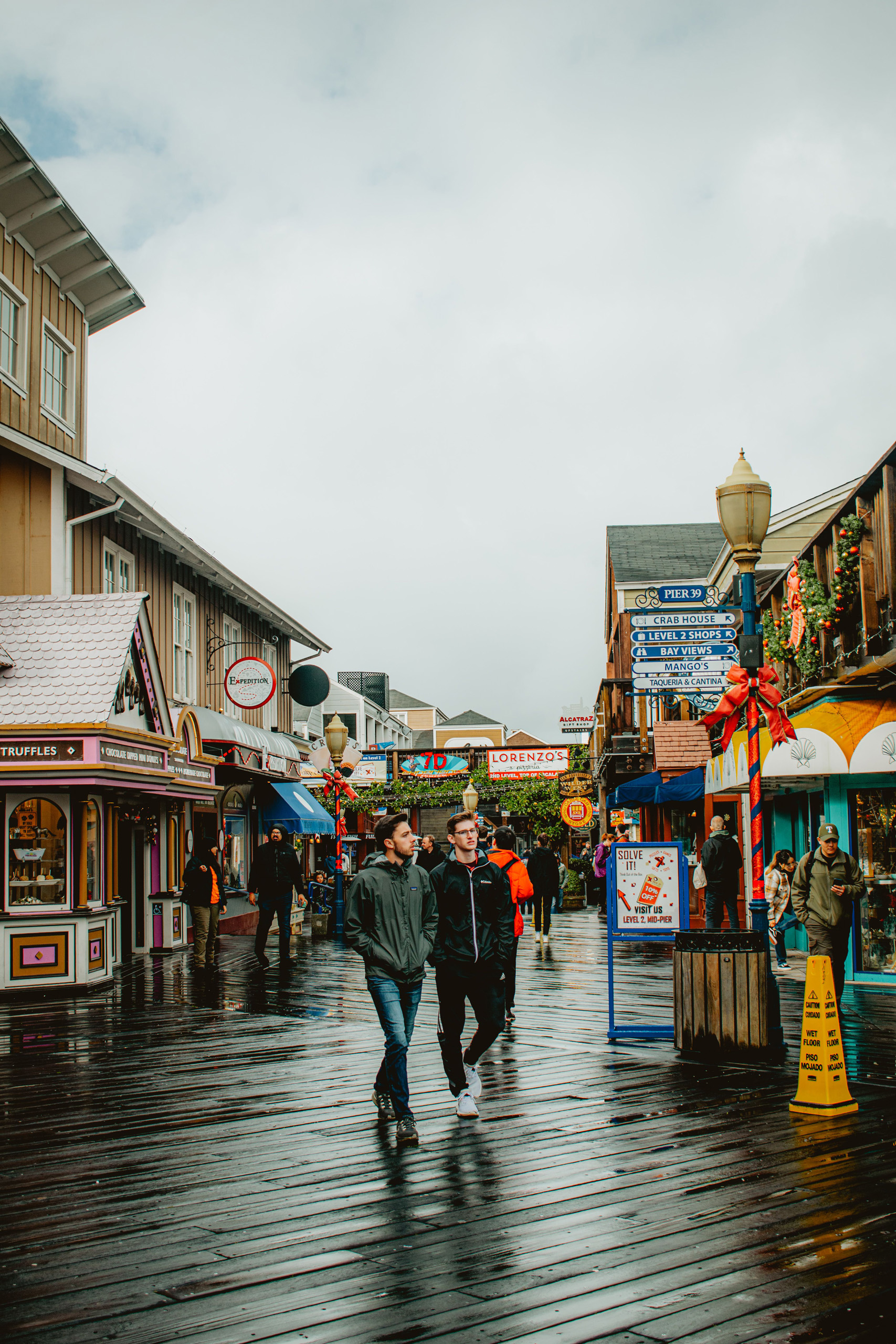 People walking along the wet boardwalk at Pier 39.