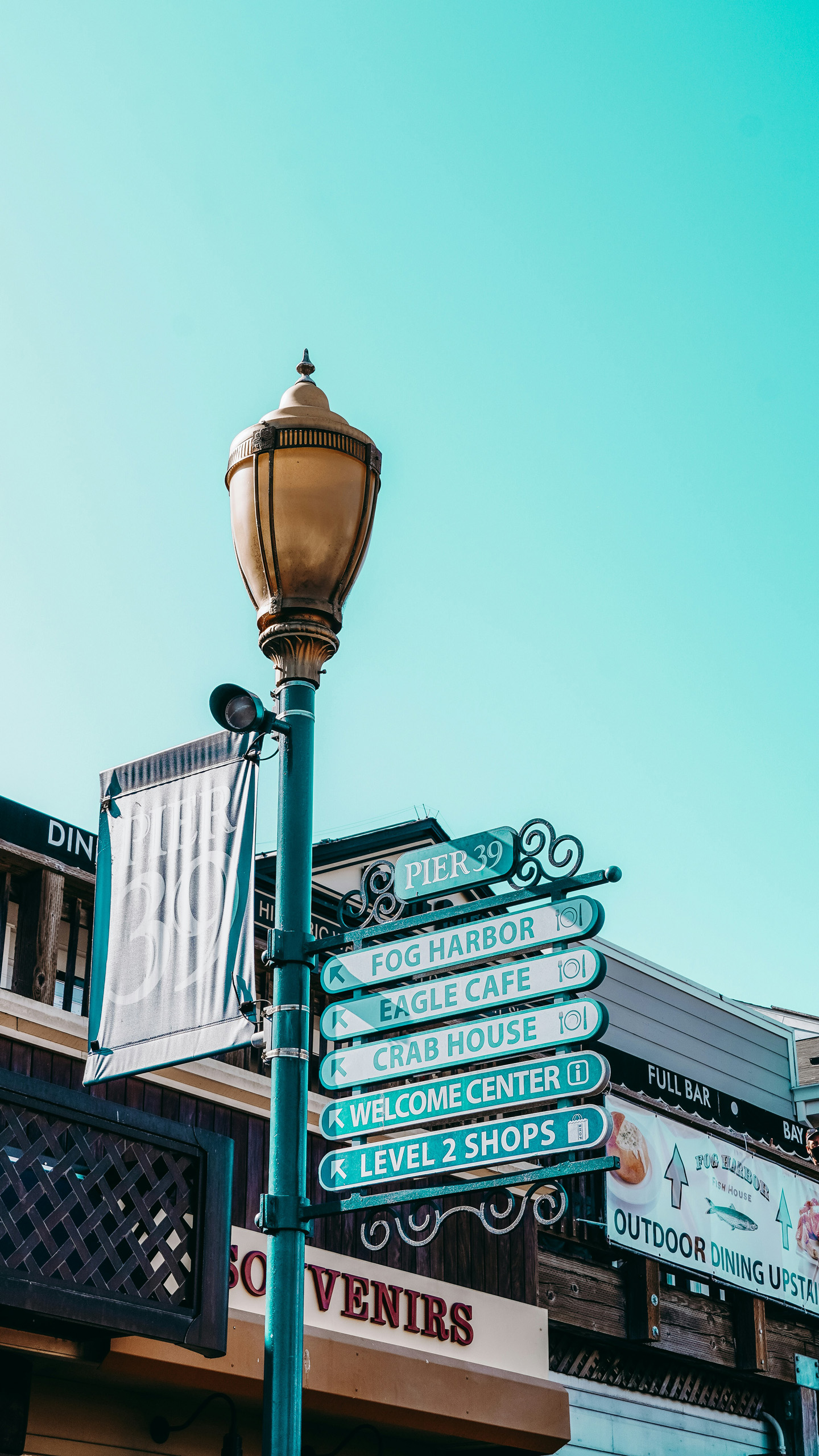 Pier 39 directional signs beside a streetlamp.