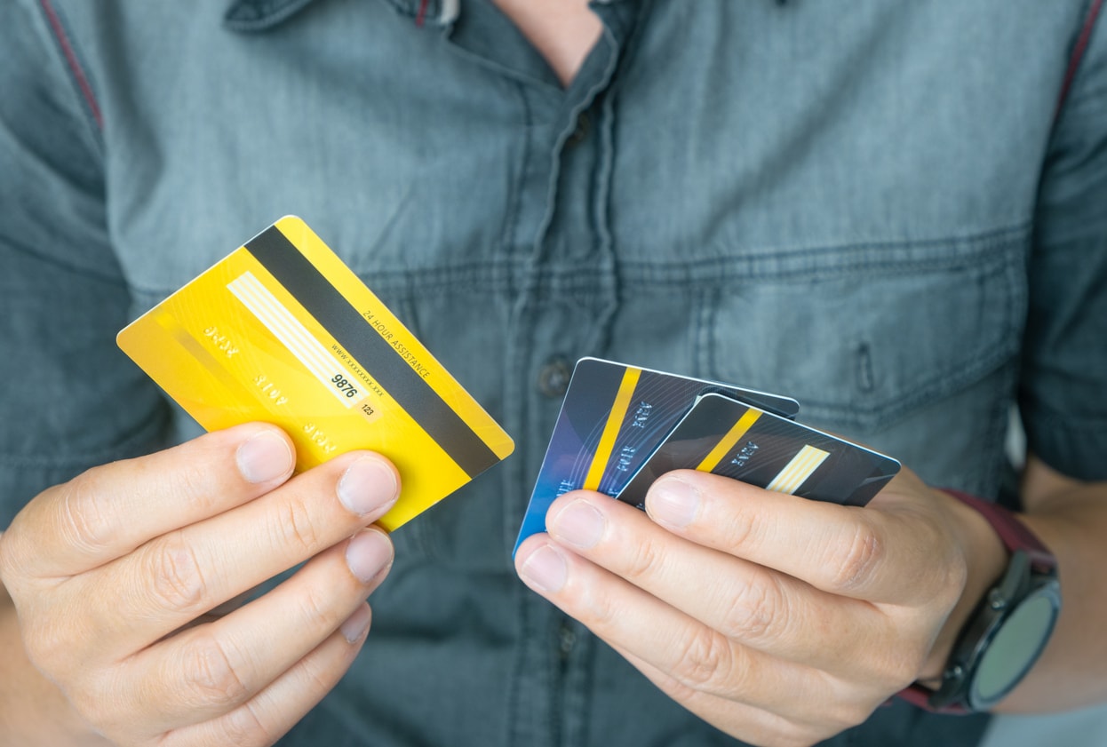 A photo of a man holding and comparing several different credit cards.