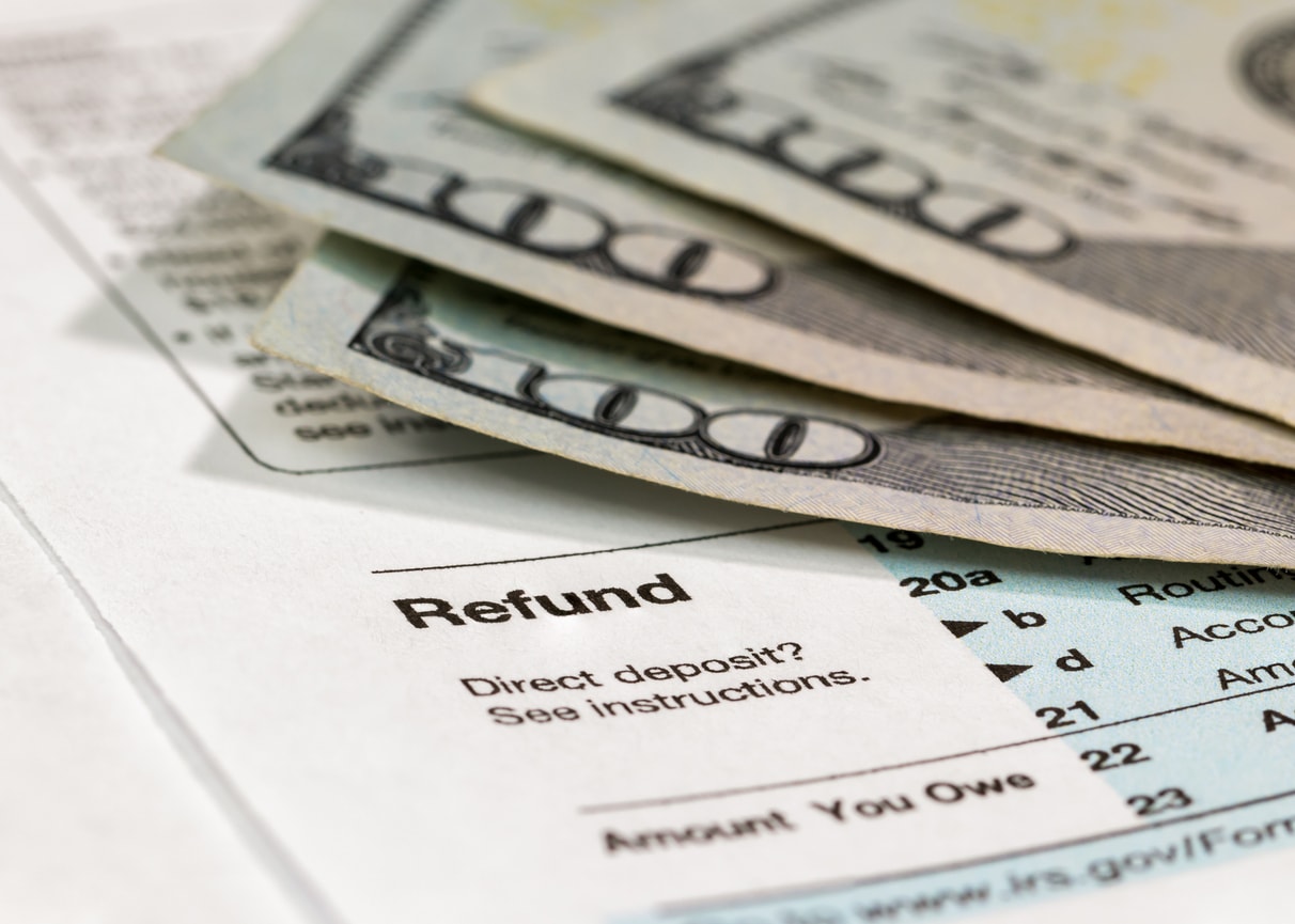 A photo of three hundred-dollar bills on top of some tax refund paperwork.