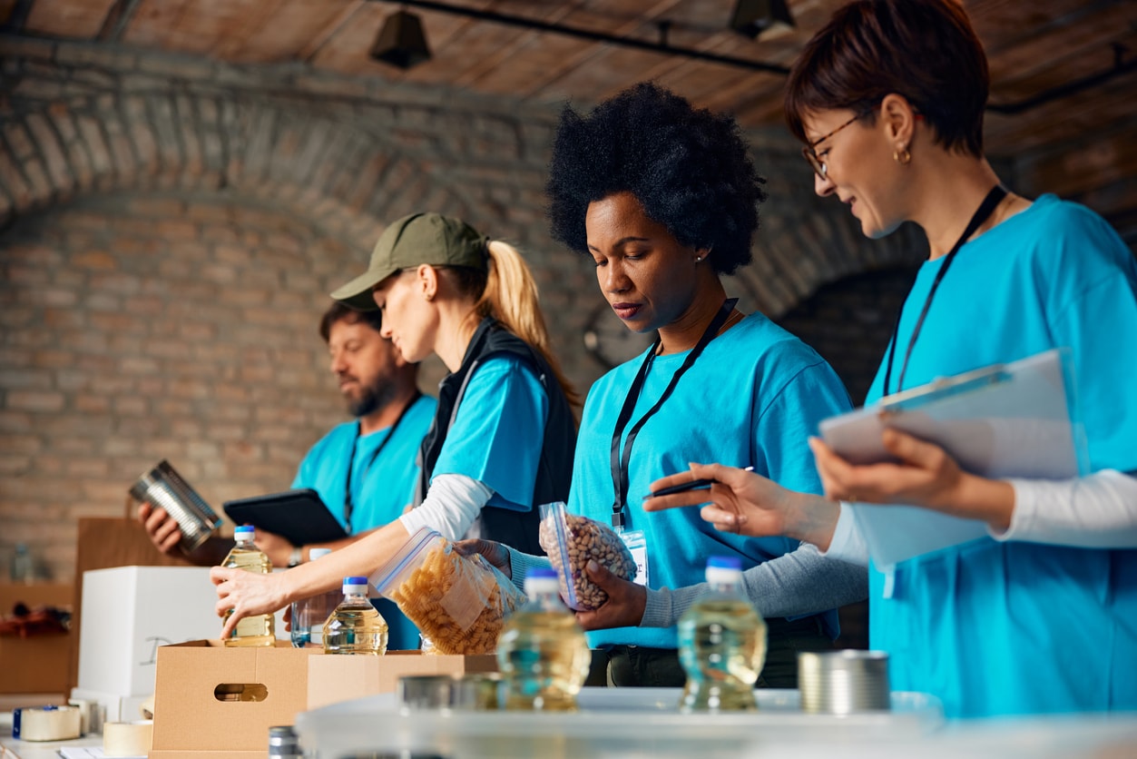 A photo of four nonprofit workers volunteering at a food drive.