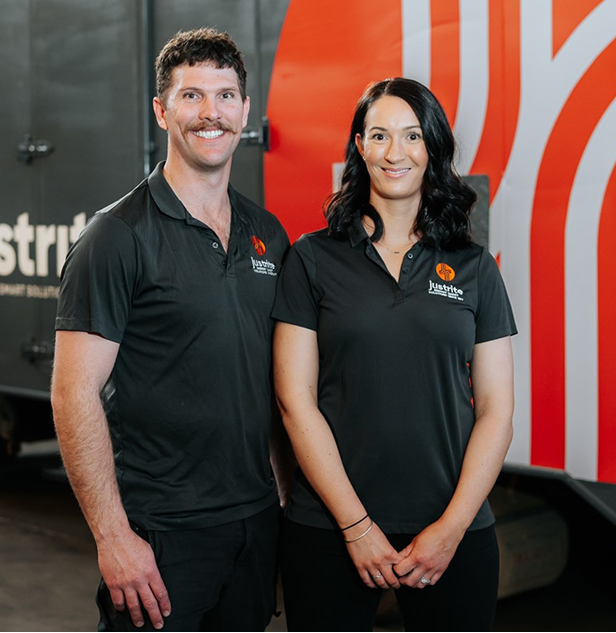 Two Just Rite team members in branded polo shirts standing in front of a company delivery truck