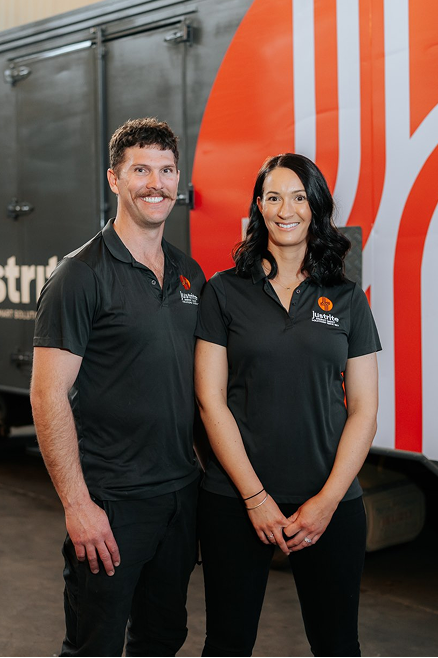 Two Just Rite team members in branded polo shirts standing in front of a company delivery truck