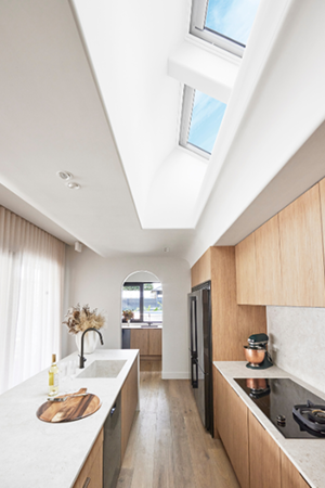 Two skylights bringing daylight into a galley kitchen with timber cabinetry and a stone benchtop