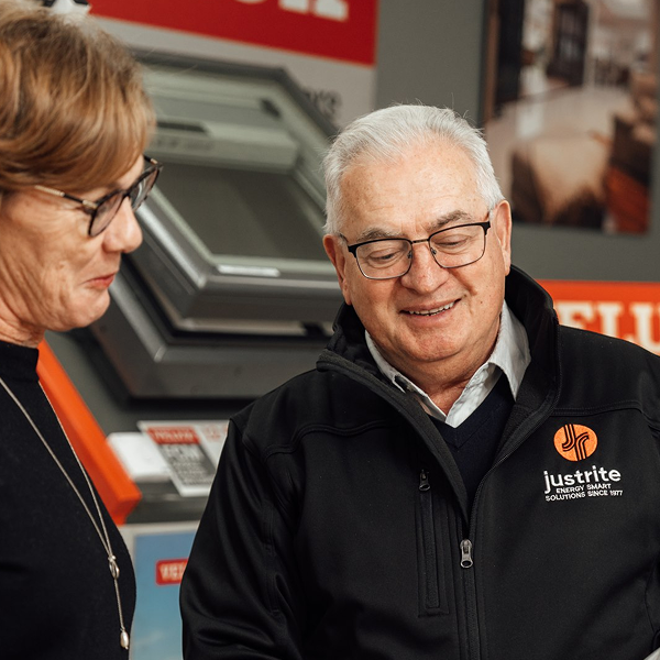 Just Rite team member in a branded jacket talking with a customer in the skylight and window showroom
