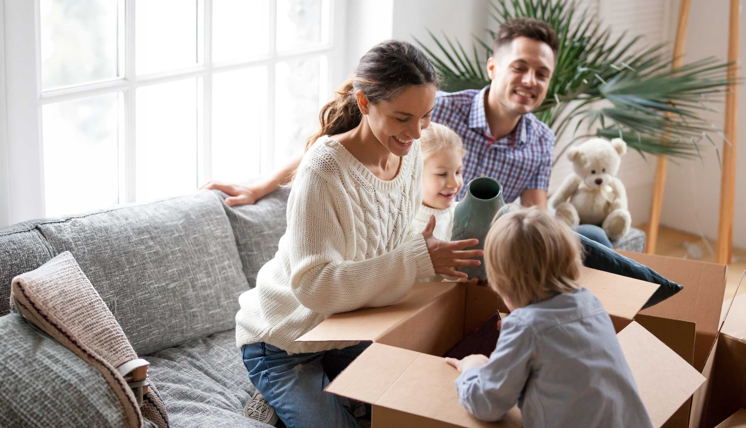 Family unpacking boxes on a lounge after moving into a rental home