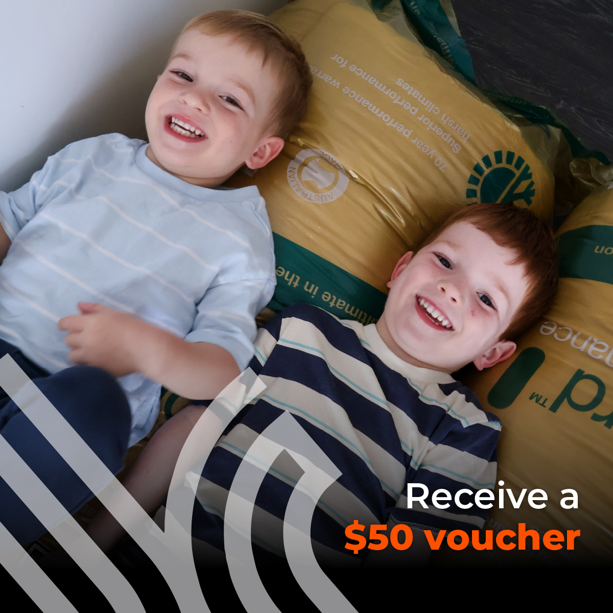 Two young children lying against bags of insulation, with a Receive a $50 voucher offer